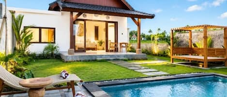 A modern house with a pool, a covered outdoor seating area, and a well-maintained lawn.