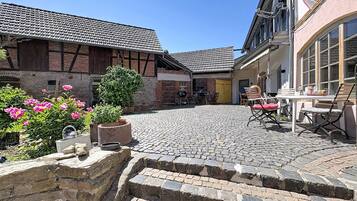 Ein Innenhof mit Kopfsteinpflaster, einer Steinsäule und einem Tisch mit Stühlen.