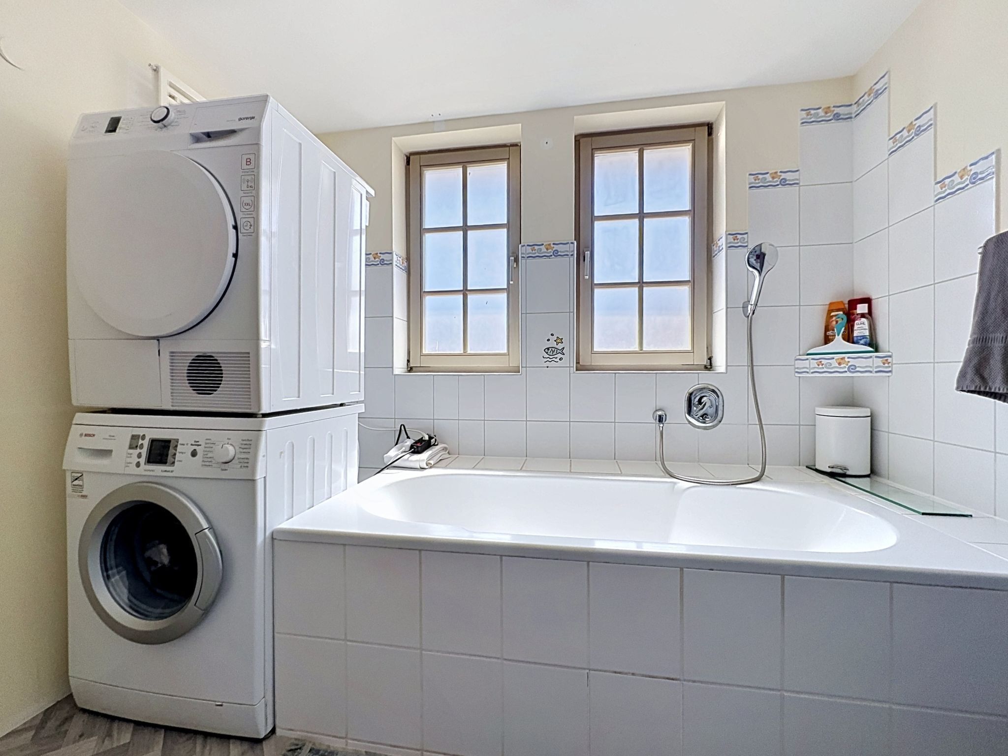 Ein kleines Badezimmer mit Waschmaschine, Badewanne und Fenster.