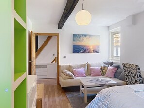 A cozy room with a sofa, a table, and a painting of a sunset.