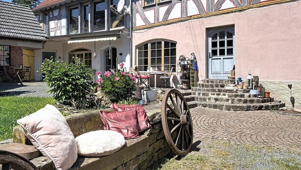 A traditional half-timbered house with a courtyard, a stone wall, and a cart. - Alte Scheune by Interhome (Idstein)