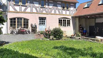 Ein traditionelles Fachwerkhäuschen mit Garten, Sitzgelegenheit im Freien und einer sichtbaren Satellitenschüssel.