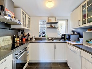 A modern kitchen with white cabinets, a black countertop, a built-in oven, a microwave, and a dishwasher. - Alte Scheune by Interhome (Idstein)