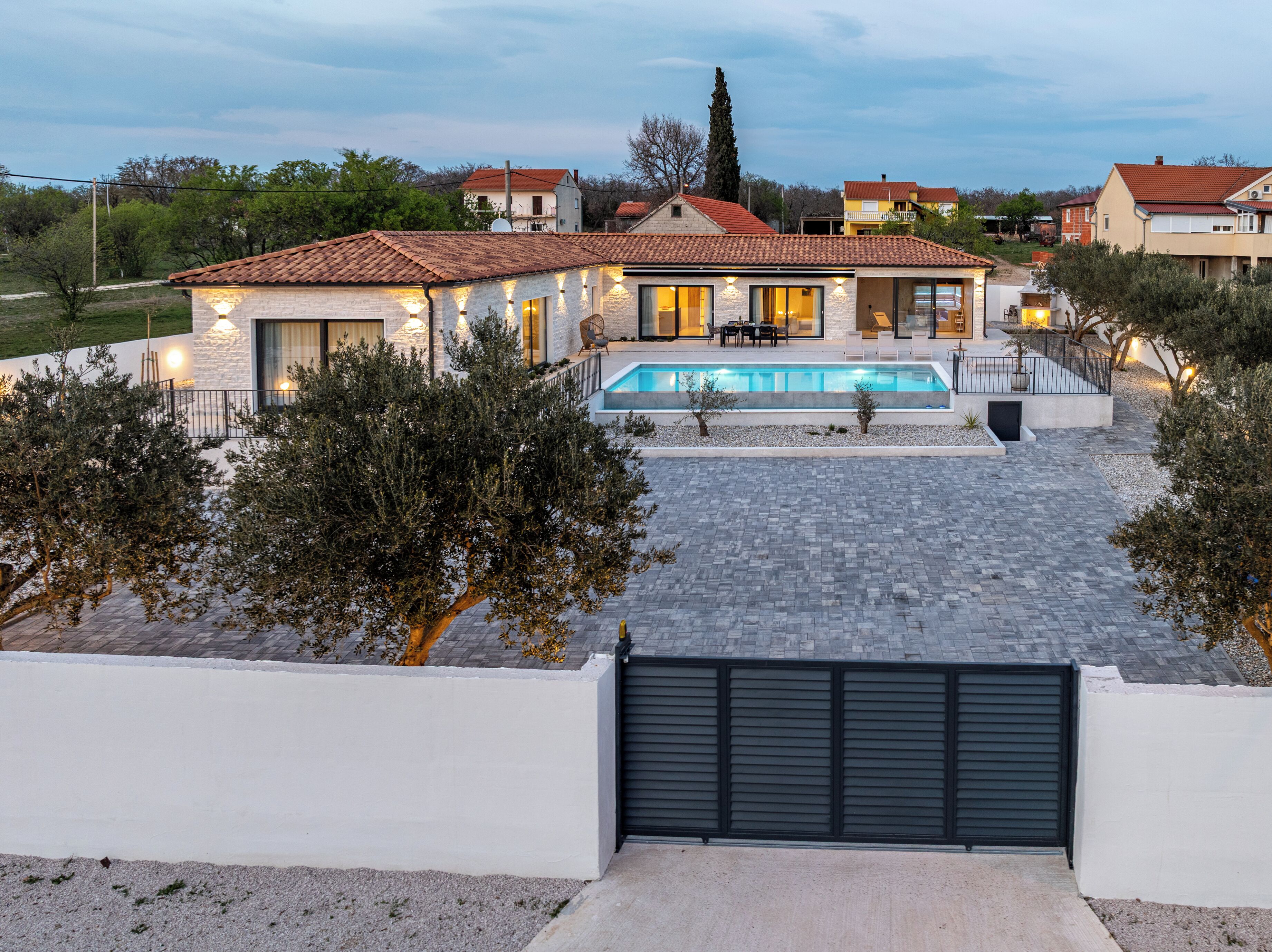 Ein modernes Haus mit Swimmingpool, einer überdachten Terrasse und einem verschlossenen Eingang.