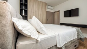 Un dormitorio moderno con cama, armario, televisor y aire acondicionado.