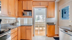 Una cucina moderna con mobili in legno, piani di lavoro in granito e forno a microonde integrato.