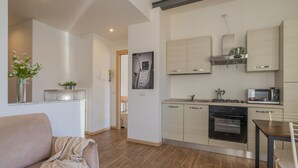A modern kitchen with built-in appliances, a dining area with a table and chairs, and a living room with a sofa. - Stunning View in Varenna (Varenna)