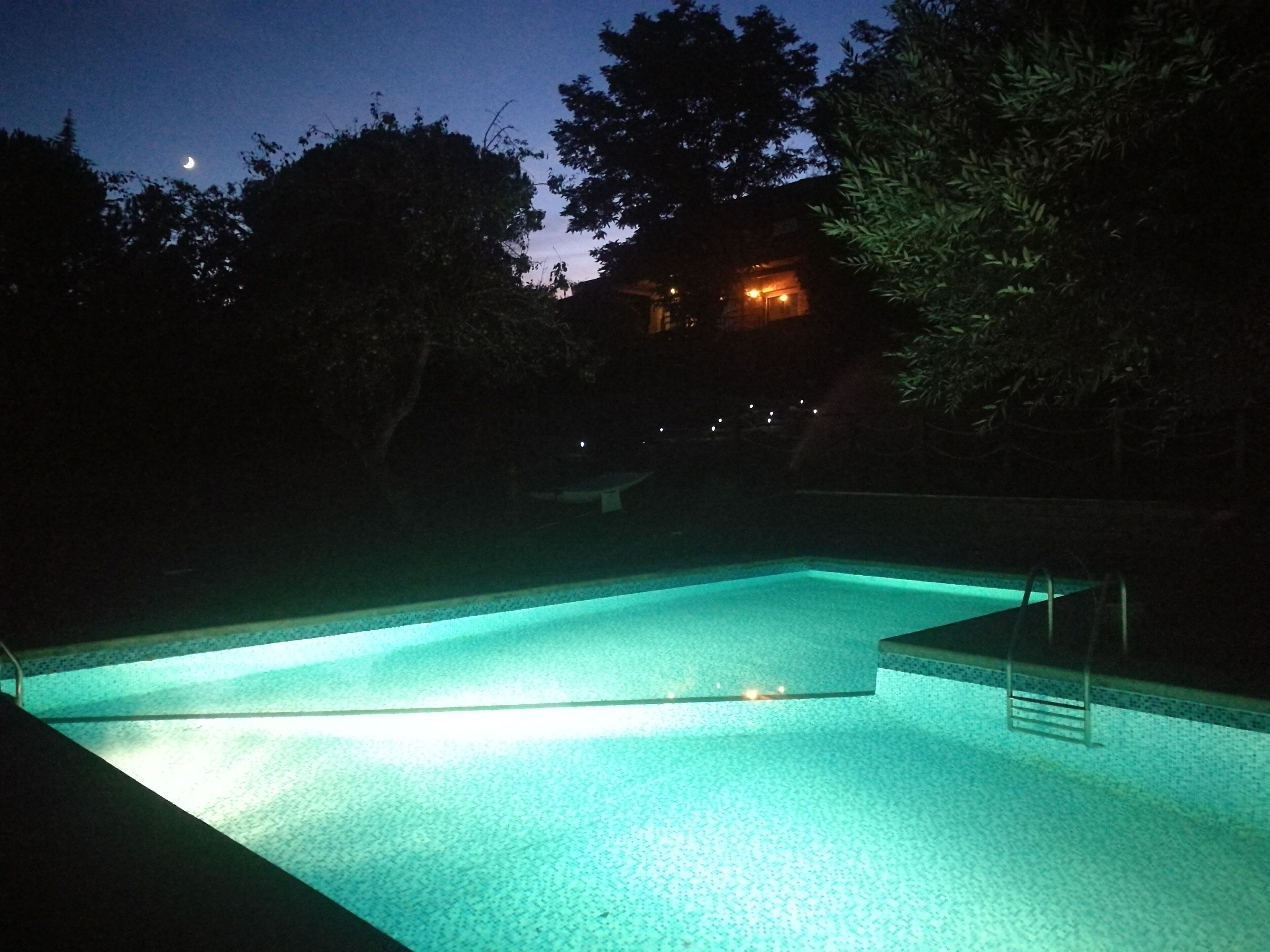 Una piscina di notte con una chiara vista della luna nel cielo.
