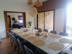 Ein Essbereich mit einem langen Tisch, Stühlen, gewobenen Platzsets und hängenden Korbtischen.