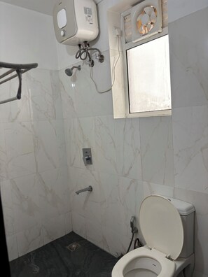 Une salle de bain avec des toilettes, une douche et une fenêtre.