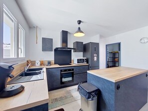 Een kleine keuken met een magnetron, broodrooster, oven en een zwarte koelkast.