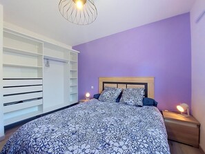A bedroom with a bed, a wardrobe, and a nightstand with a lamp. - Le Bayonnais by Interhome (Bénesse-Maremne)