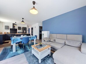 Een moderne woonkamer met een bank, een salontafel en een eethoek met stoelen en een tafel.