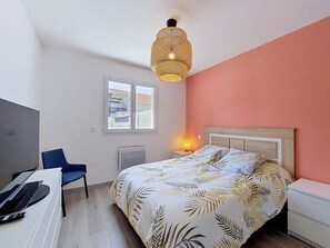 Een slaapkamer met een bed, een bureau, een stoel, een raam en een plafondlamp.