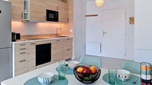 Eine moderne Küche mit Holzausstattung, einer Mikrowelle und einem Essbereich mit Tisch für zwei Personen.