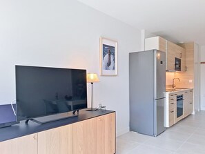 Ett modernt kök med en platt-TV, en lampa och en inramad tavla på väggen.