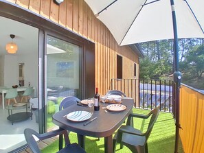 Ein Essbereich im Freien mit einem Tisch für vier Personen, einer Glastür zu einem Raum und einer Holzterrasse.