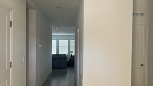 A hallway with a dark grey tiled floor, white walls, and a grey sofa in the background. - Spacious 4-bedroom house in amazing Davenport with AC (Davenport)