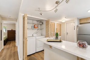 A modern kitchen with built-in appliances, a central island, and a laundry area. - Vega Apartment Seattle (Seattle)