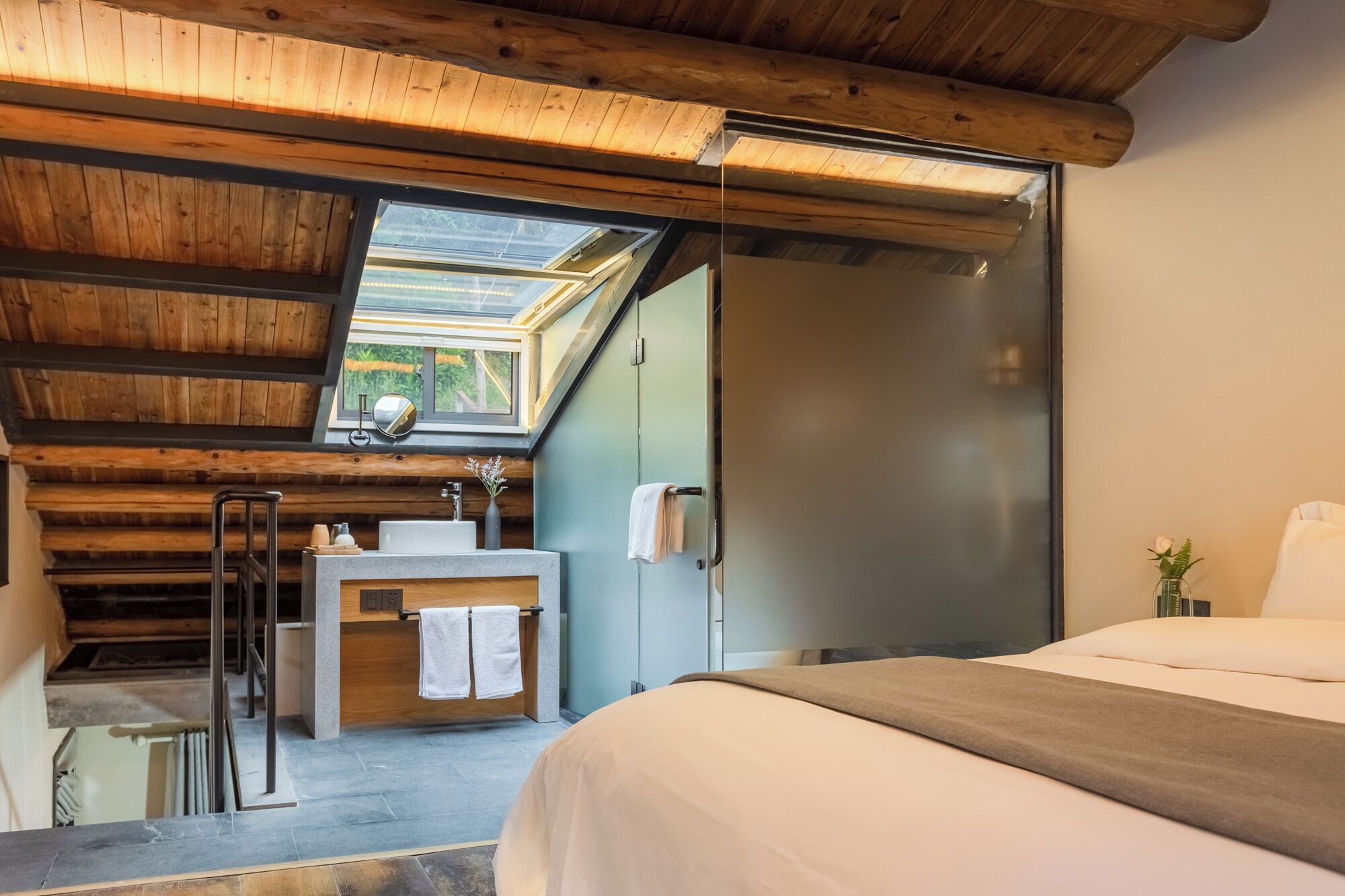 Un dormitorio con tragaluces, un baño con espejo y una cama.