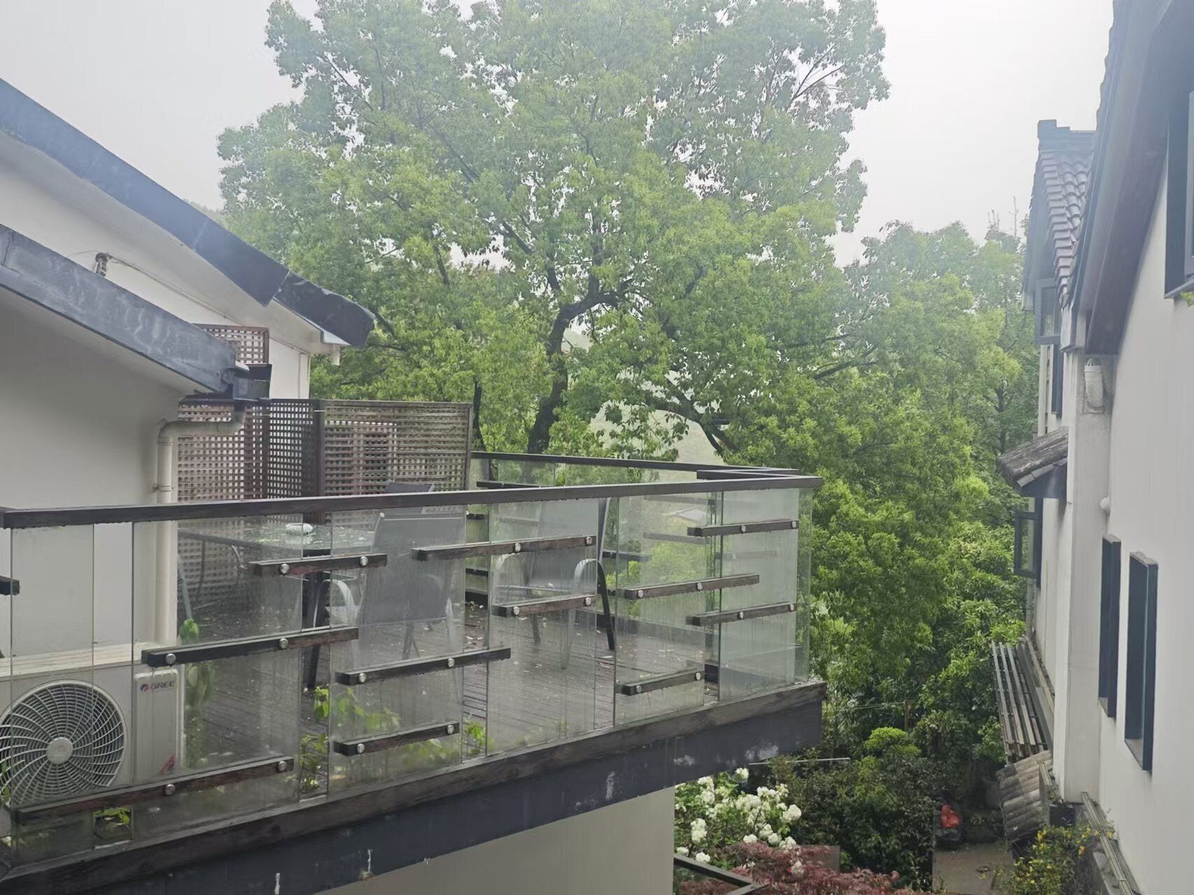 A residential building with a balcony, a fan, and a garden area.