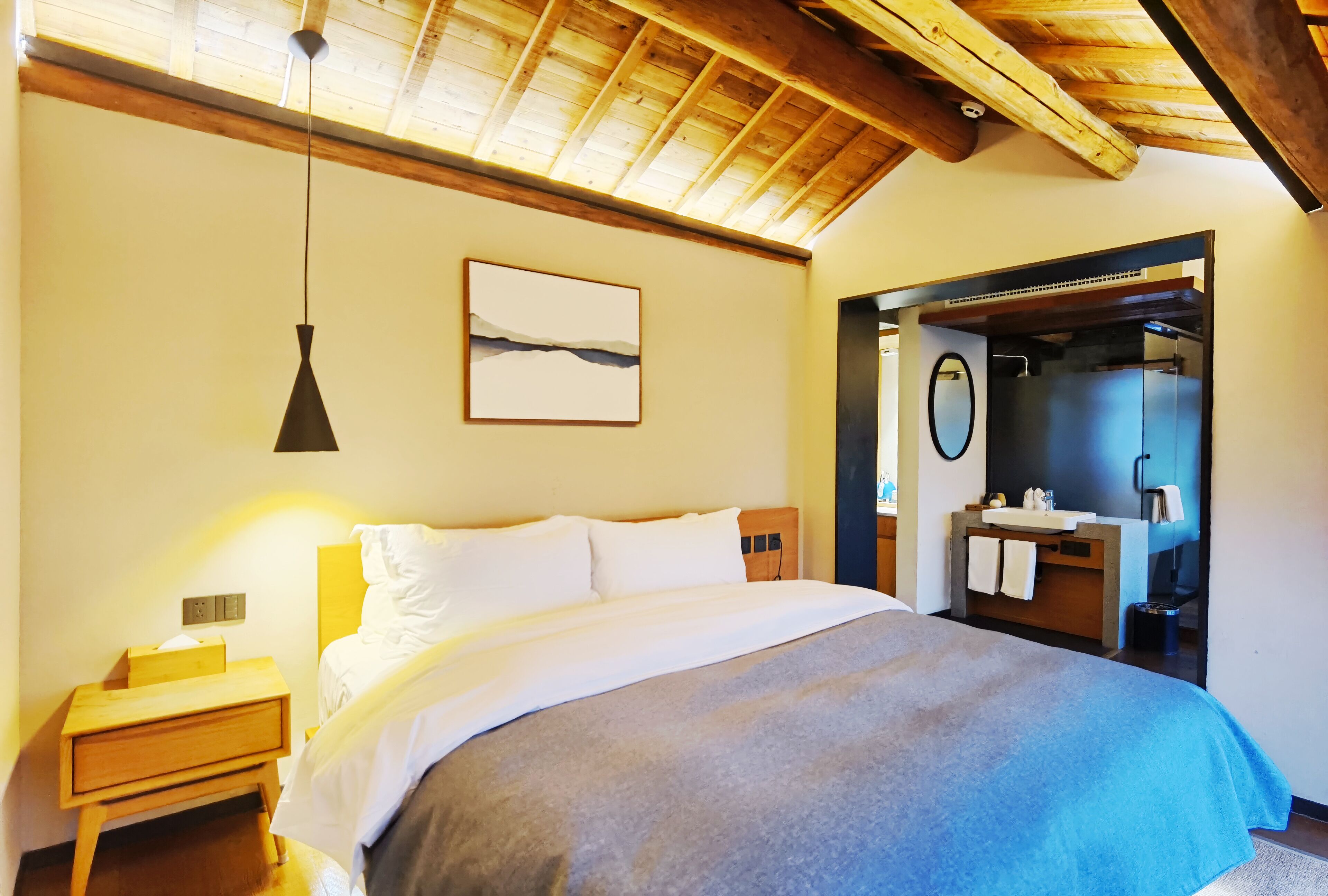 A bedroom with a bed, bedside table, and a mirror.