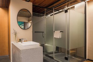 A modern bathroom with a glass shower enclosure, a round mirror, and a granite sink. - WuTiaXinShe Guesthouse West Lake Branch (Hangzhou)