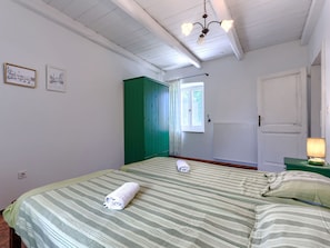 A bedroom with a bed, a green wardrobe, a window, a radiator, and a lamp. - Villa Krase by Interhome (Svetvinčenat)