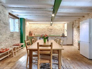 A rustic kitchen with a stone wall, wooden table, chairs, and a refrigerator. - Villa Krase by Interhome (Svetvinčenat)