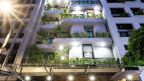 A multi-story building with outdoor seating, a restaurant, and balconies with plants. - Nani's Hotel & Apartment (Da Nang)