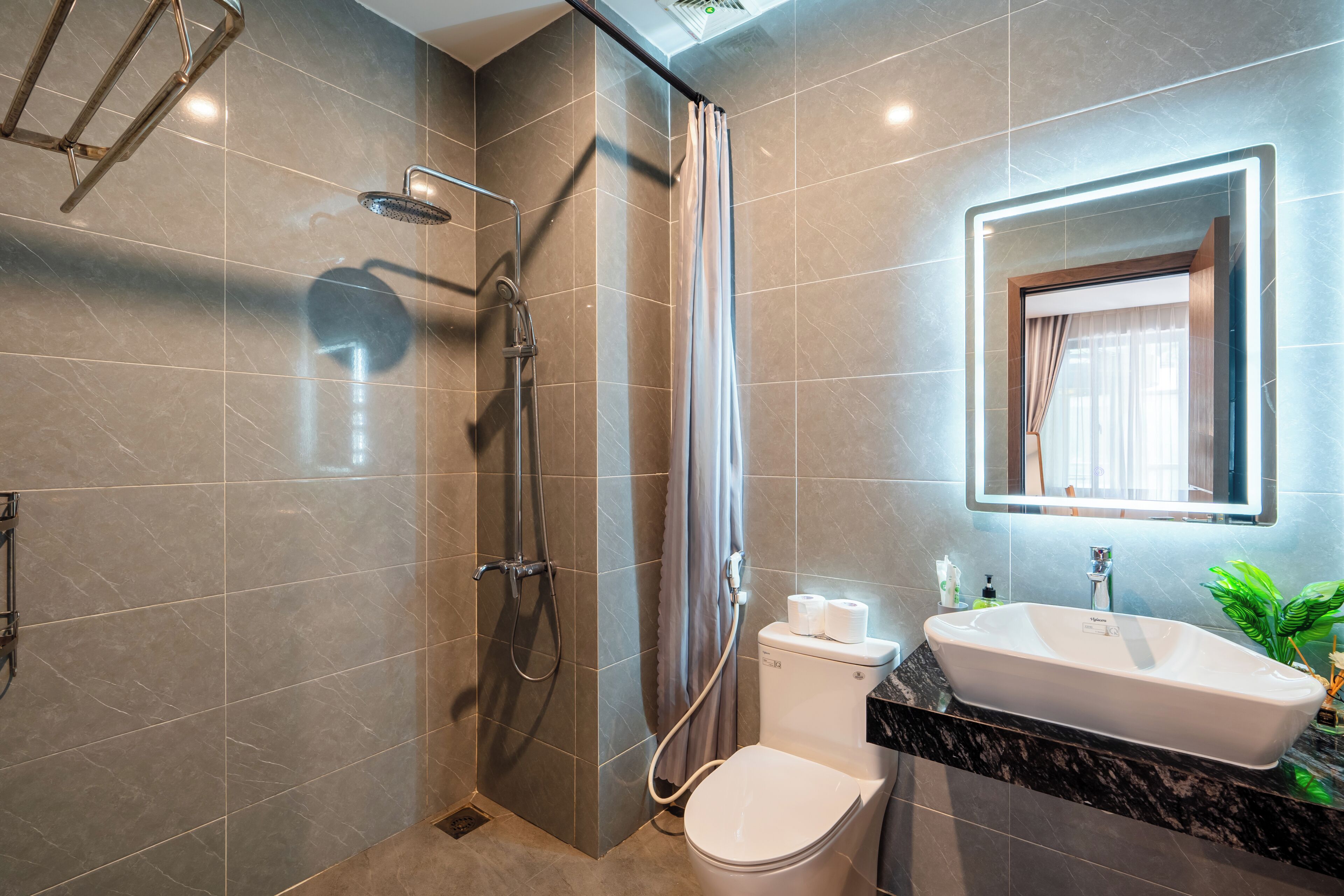 Un baño moderno con ducha, inodoro, lavamanos y espejo.