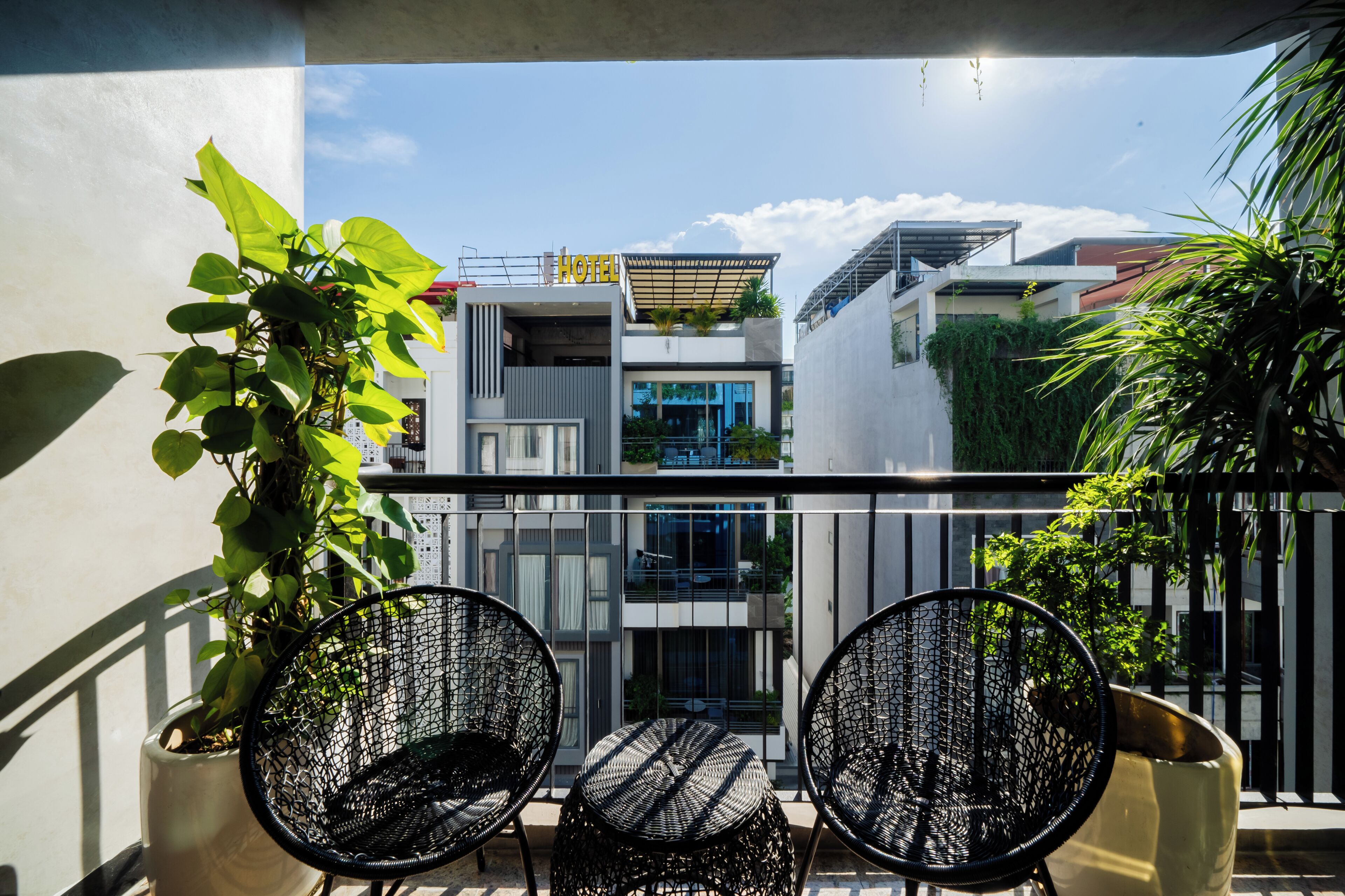 A balcony with two black wicker chairs, a small table, and potted plants.