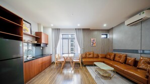 A modern kitchen with a dining area, a leather sofa, and a patterned rug. - Nani's Hotel & Apartment (Da Nang)