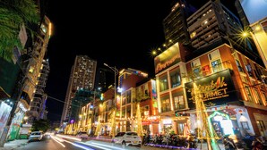 A brightly lit street with buildings, including a restaurant with outdoor seating and a sign. - Nani's Hotel & Apartment (Da Nang)