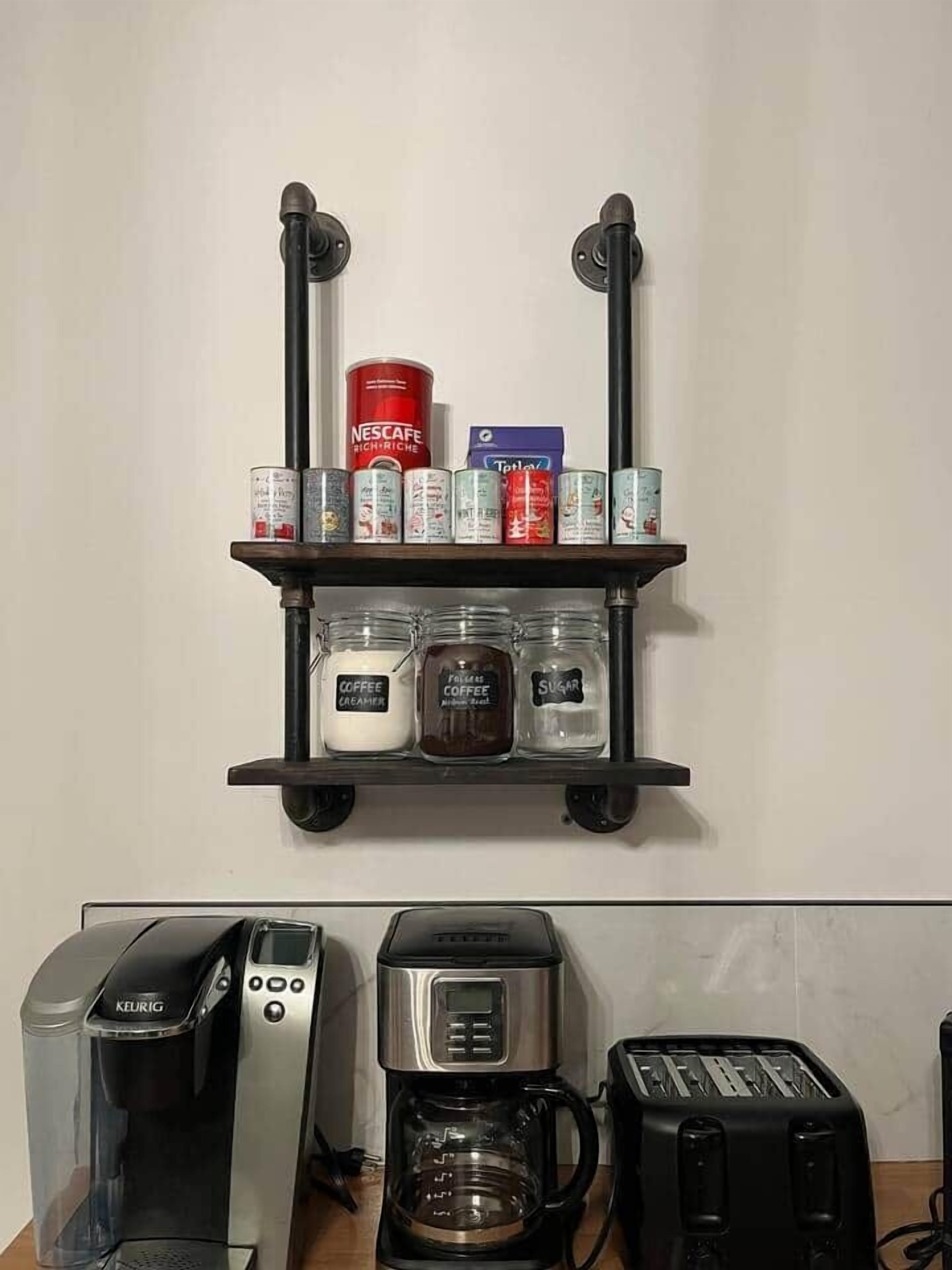 A kitchen with a coffee machine, toaster, and a shelf with coffee creamer, sugar, and Nescafe cans.