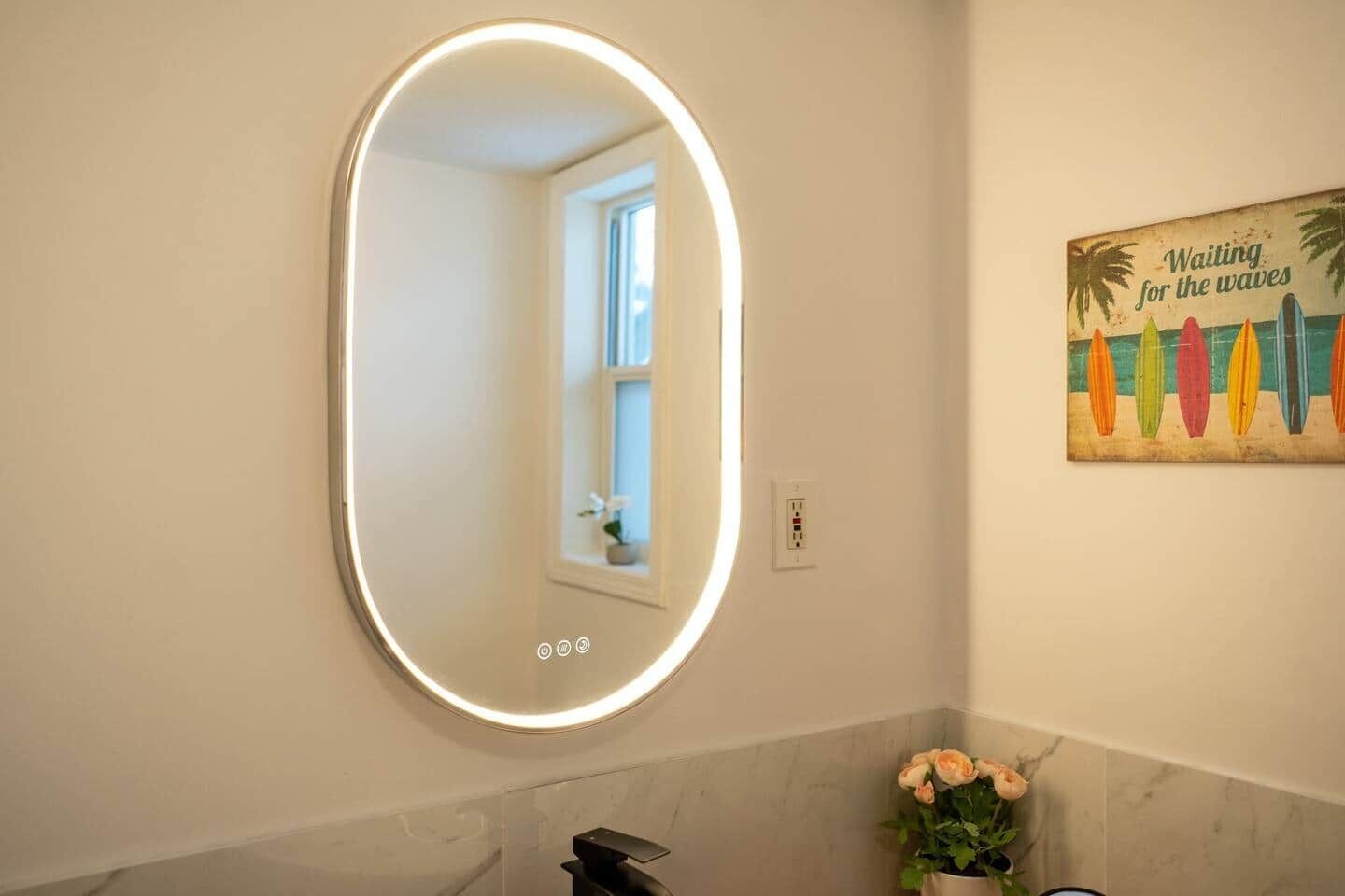 A bathroom with a round mirror, a flower vase, and a wall art piece.