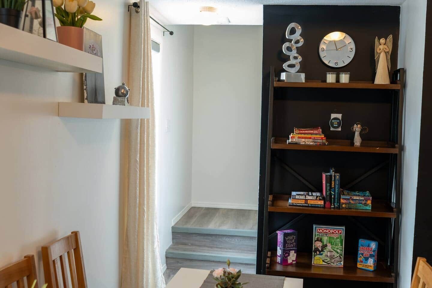 A room with a bookshelf, a clock, and a small angel statue.