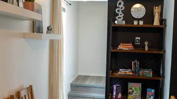 A room with a bookshelf, a clock, and a small angel statue.
