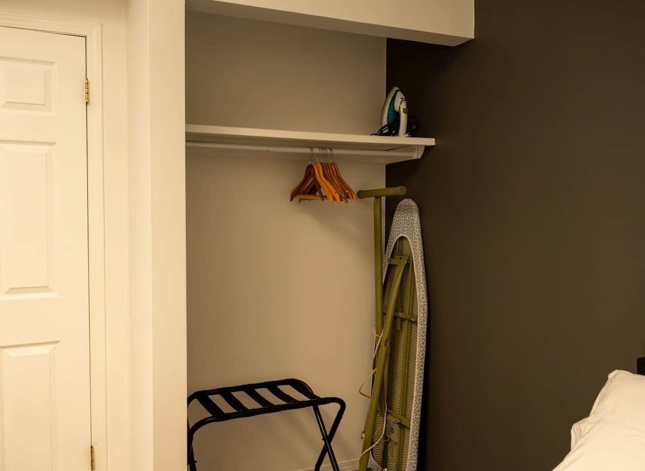 Ein Zimmer mit weißer Tür, einem Kleiderständer und einem Regal mit einem kleinen Gegenstand.