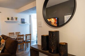 A living room with a brown sofa, a round mirror, and decorative vases on a wooden console. - Cozy 2Br Home near Downtown WPG | Free Parking (Winnipeg)