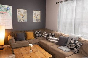 Ein gemütliches Wohnzimmer mit einem Ecksofa, einem Couchtisch aus Holz und zwei an der Wand befestigten Bildern.