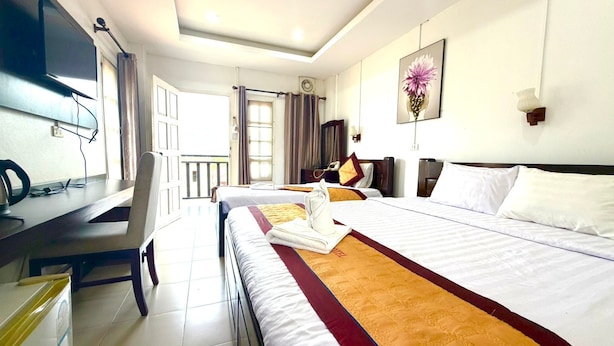 A hotel room with a bed, a desk, a TV, and a window. - Cozy Corner Hotel (Vang Vieng)