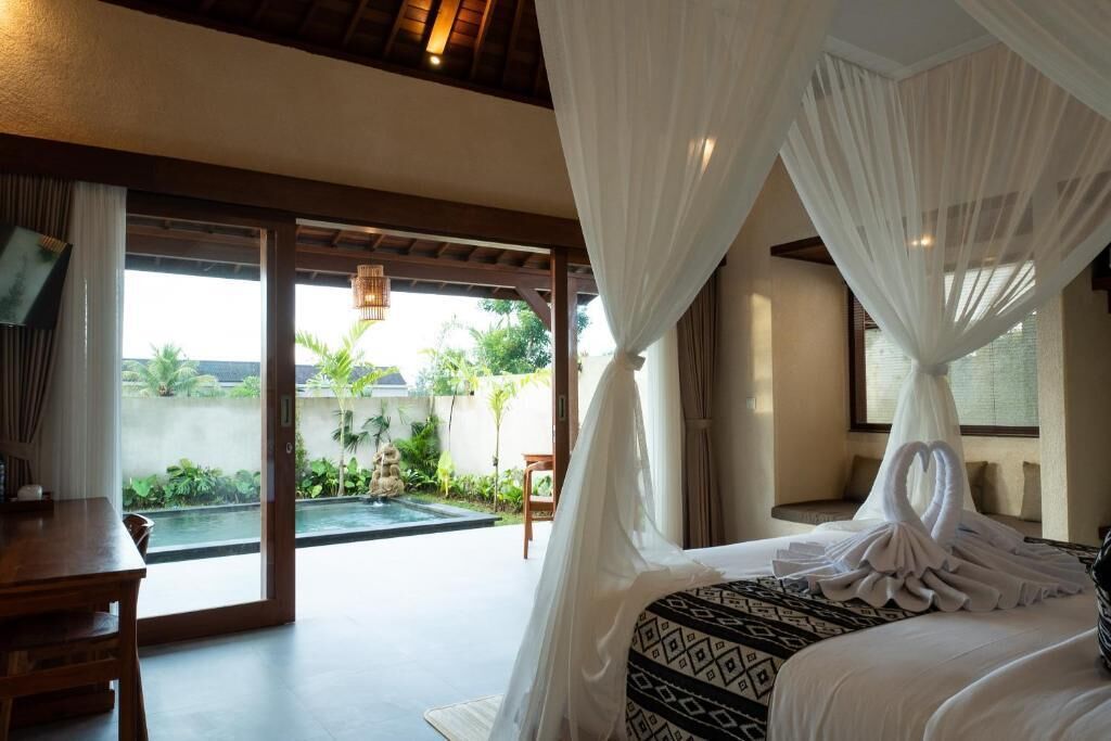 Une chambre avec un lit, un bureau et une vue sur un jardin et une piscine.