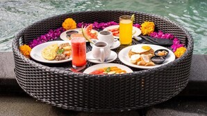 Una cesta de mimbre con diversos alimentos y bebidas sobre una mesa junto al agua.