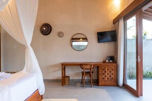 Ein Schlafzimmer mit Bett, Schreibtisch, Stuhl, Fernseher und einer Schiebetür.