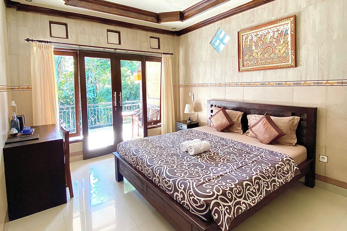 Un dormitorio amplio con una cama grande, un escritorio con silla y un balcón con vistas.