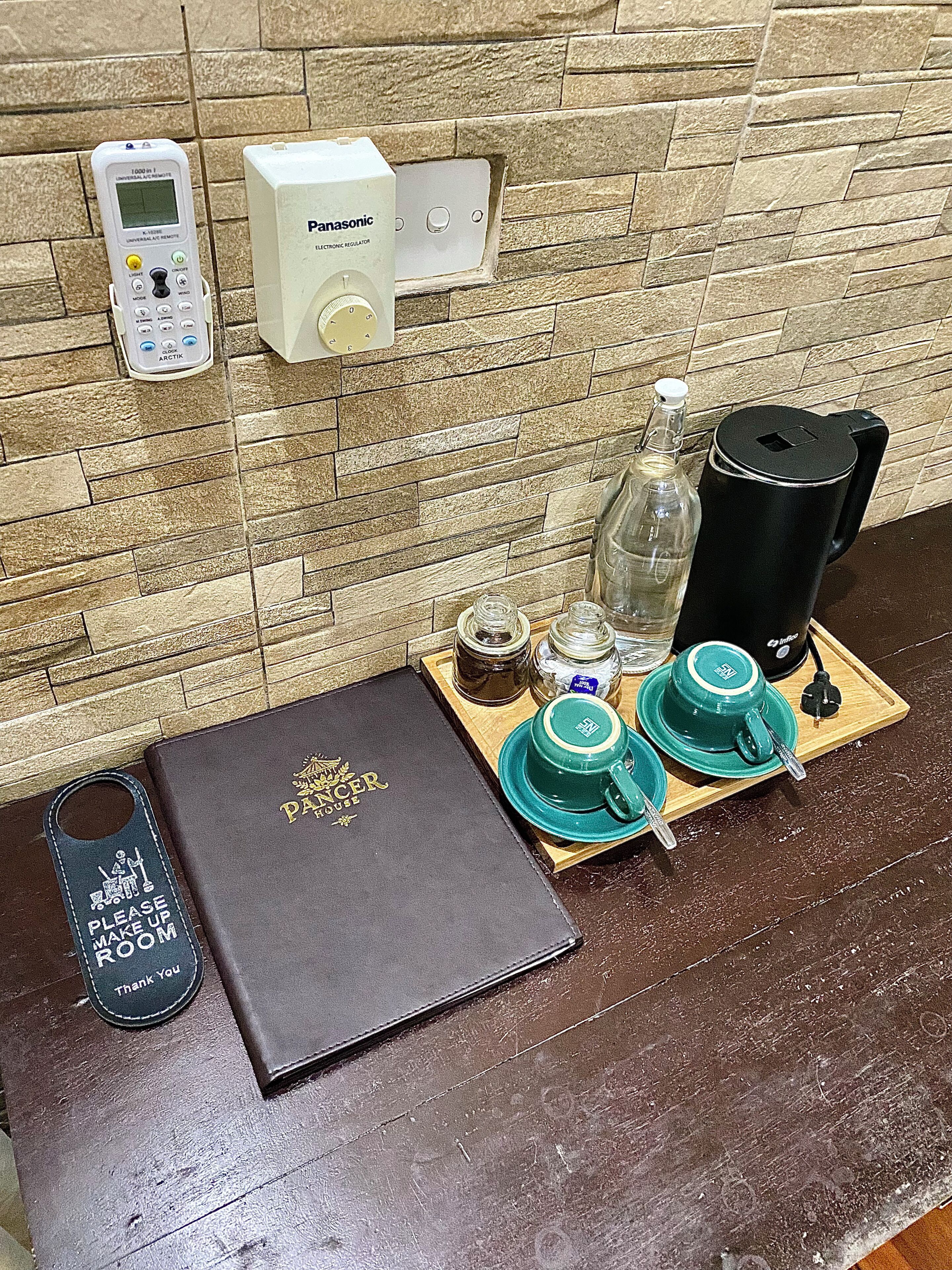 Un plateau de petit-déjeuner avec une théière, des tasses, un thermos et un livre, posé sur une table en bois.