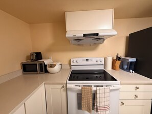 A kitchen with a stove, microwave, toaster, and a range hood.