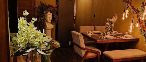 A dining area with a wooden table, chairs, and a vase with flowers.
