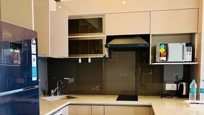 A modern kitchen with a dishwasher, a microwave, and a refrigerator. - Aravali Hill CherisingBeauty 1BHK CP3Flower Valley (Gurugram)